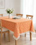 Orange and white geometric diamond pattern handloom cotton table cover featuring decorative fringe tassels along the edge.