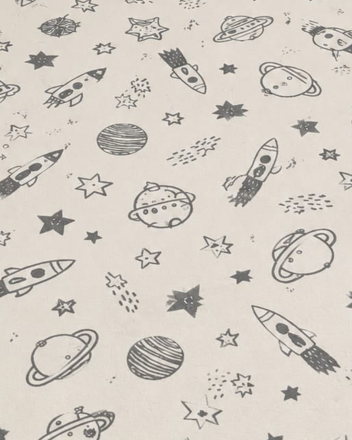 Off-white cotton area rug with charcoal outer space rocket and planet prints styled in a cozy kids nursery setting
