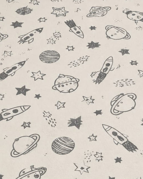 Off-white cotton area rug with charcoal outer space rocket and planet prints styled in a cozy kids nursery setting