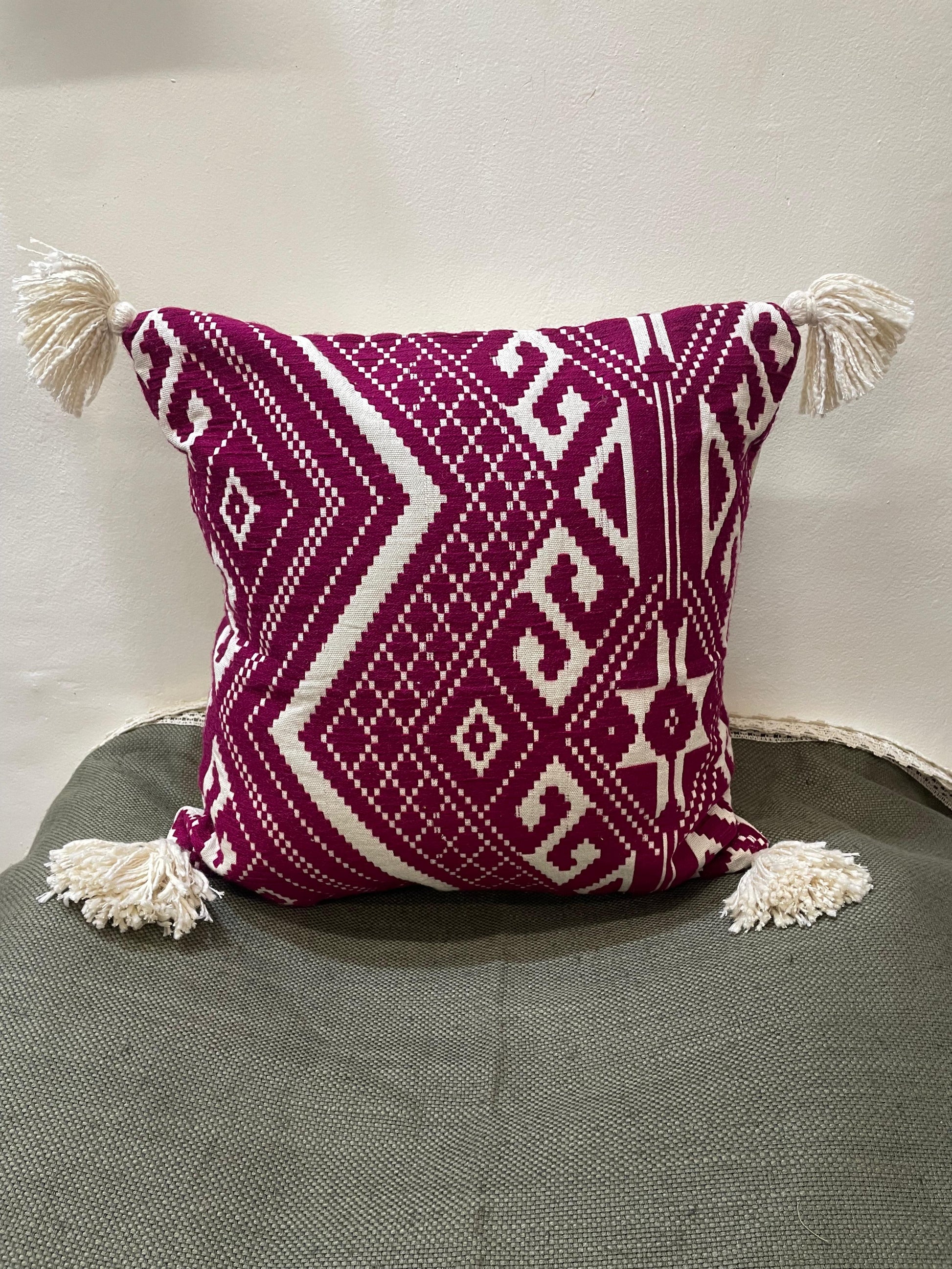 Decorative pillow with geometric pattern and tassels on a gray surface