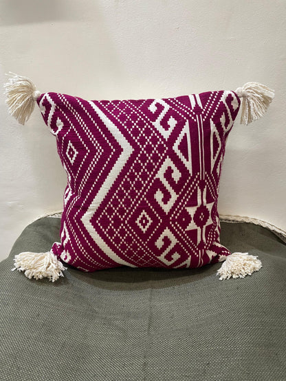 Decorative pillow with geometric pattern and tassels on a gray surface