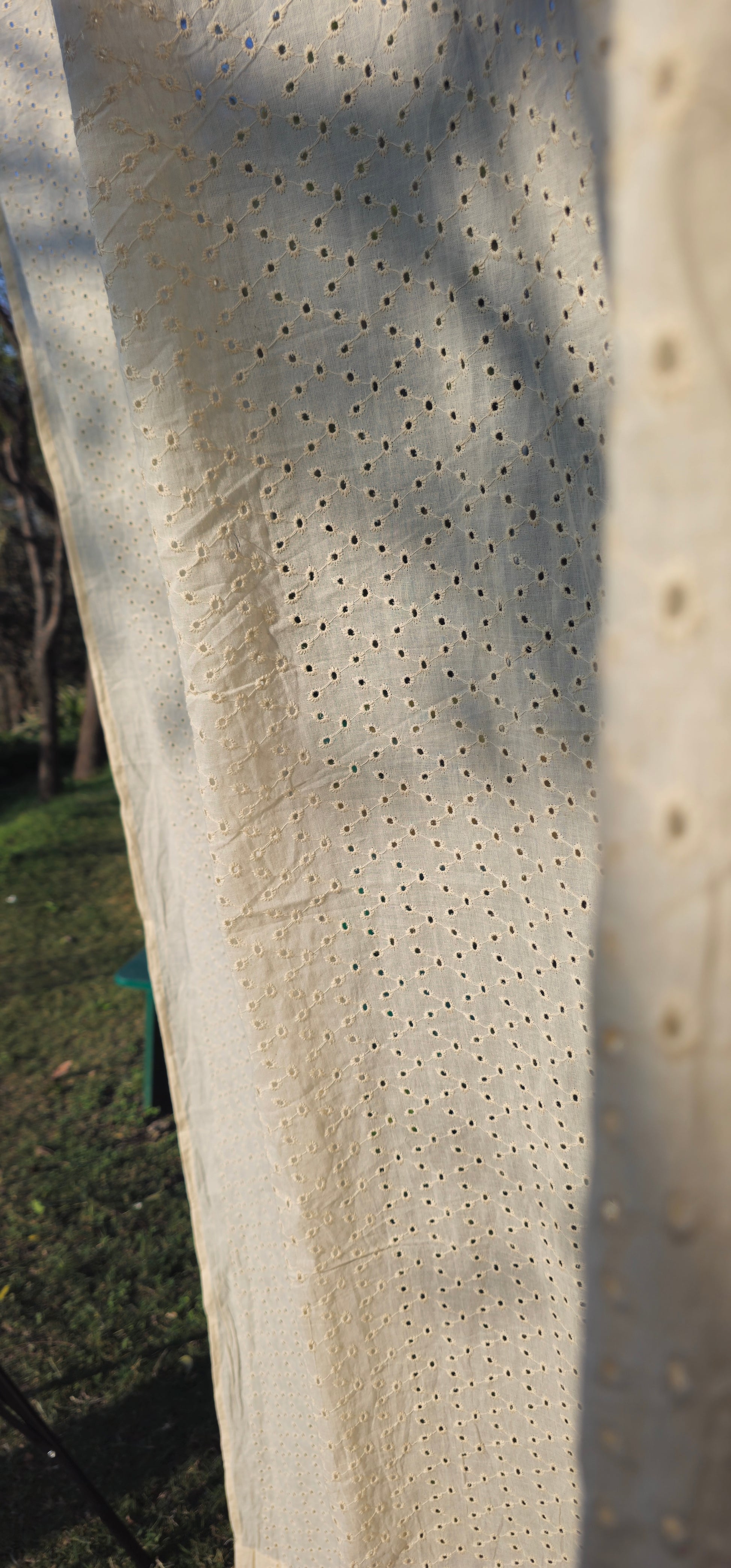 Close-up of a textured white surface with small holes, possibly fabric or paper.