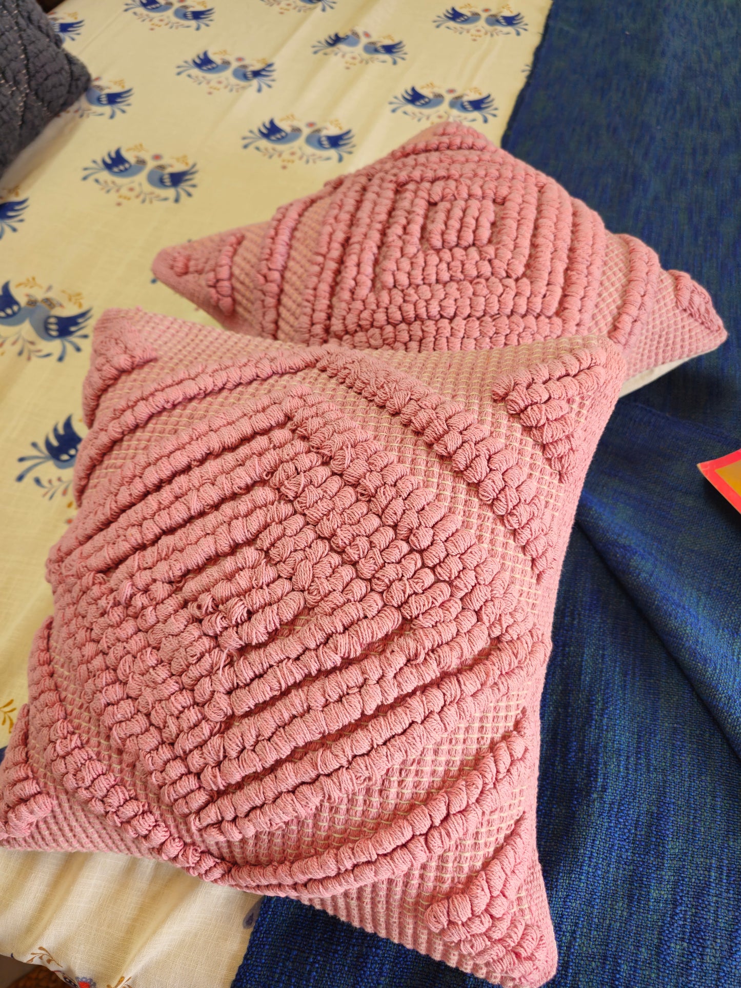 Pink textured pillow on a bed with floral patterned sheets