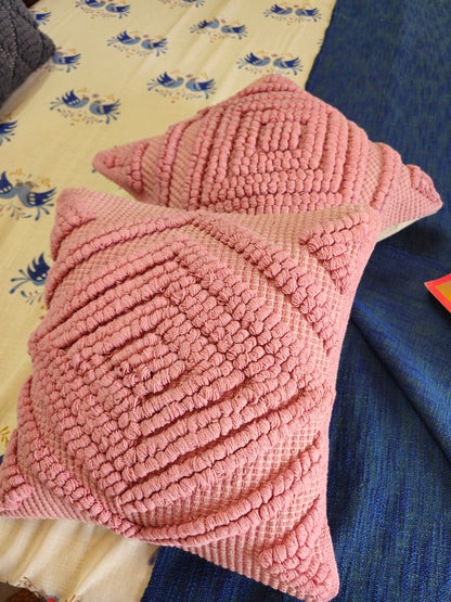 Pink textured pillow on a bed with floral patterned sheets