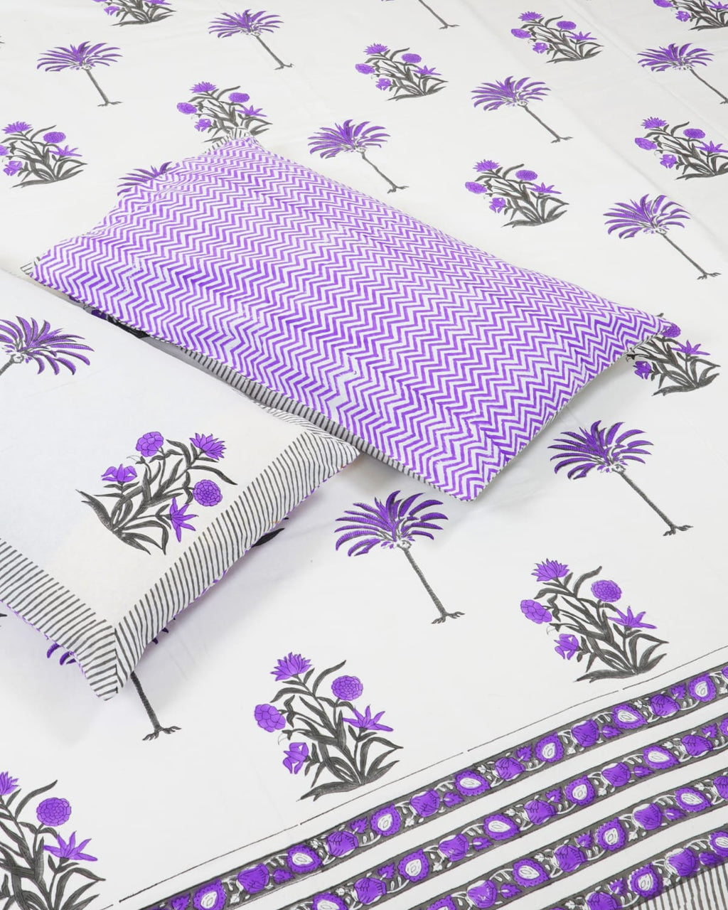 100x108 inch king size cotton bedsheet and matching chevron pillow covers styled with a traditional purple floral and palm tree handblock print.