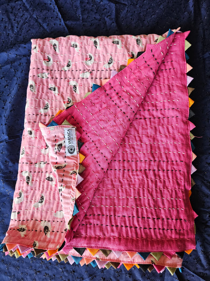 Pink quilt with colorful edges on a dark blue background