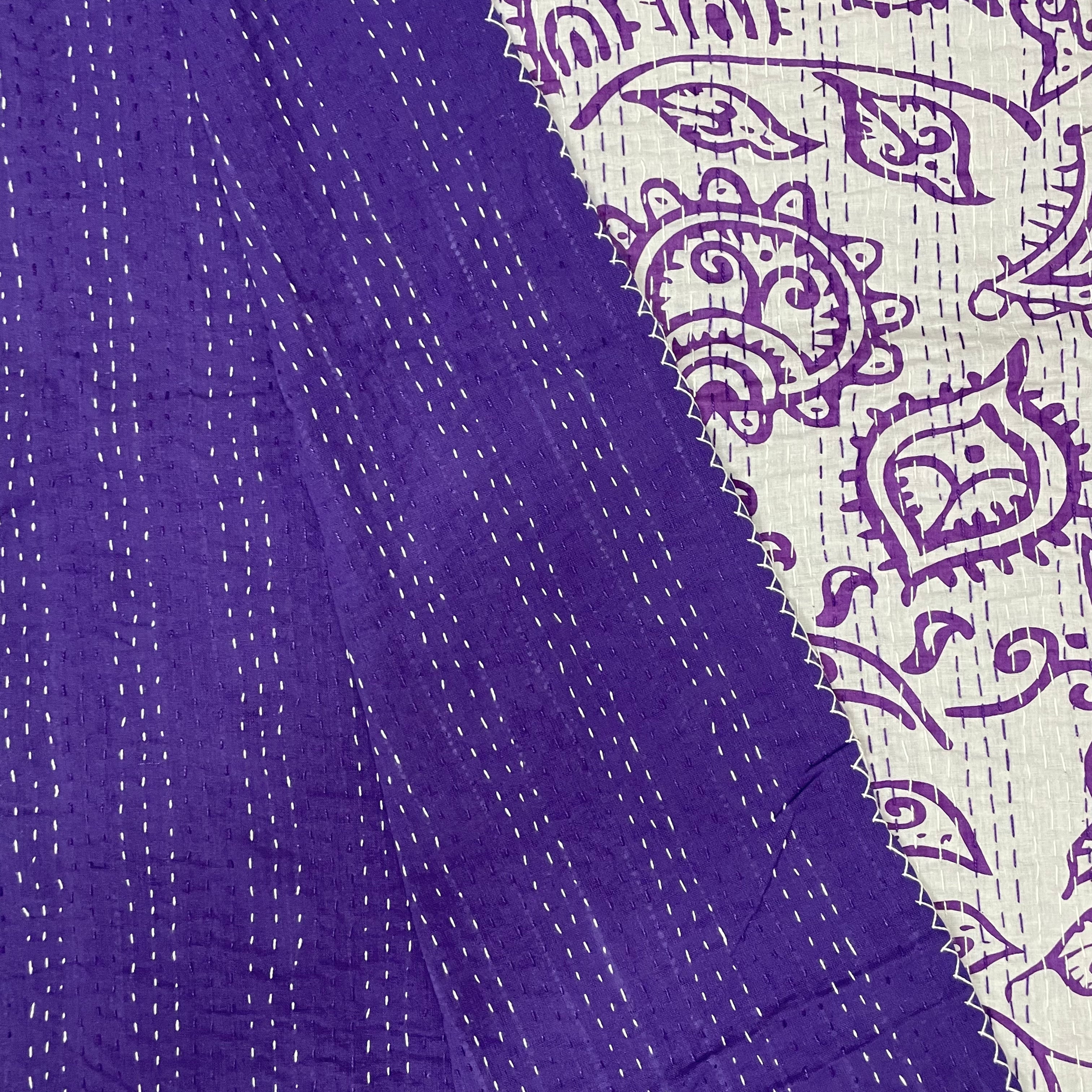 Close-up of purple fabric with white stitching and a patterned border