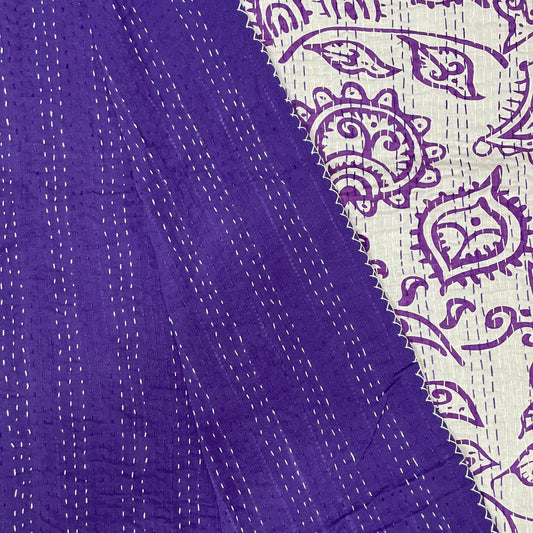 Close-up of purple fabric with white stitching and a patterned border