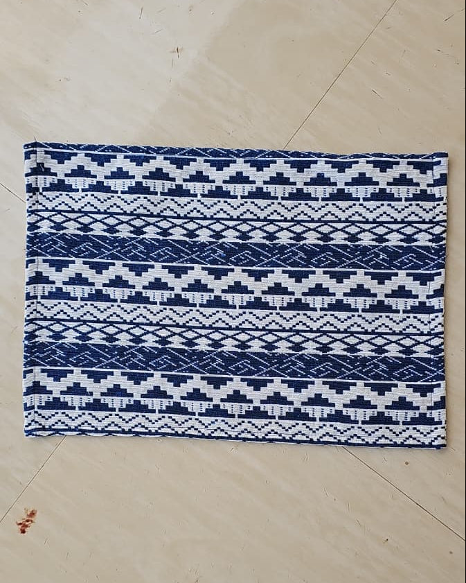 Close-up view of a royal blue and off-white woven cotton placemat featuring a detailed geometric Aztec jacquard pattern.