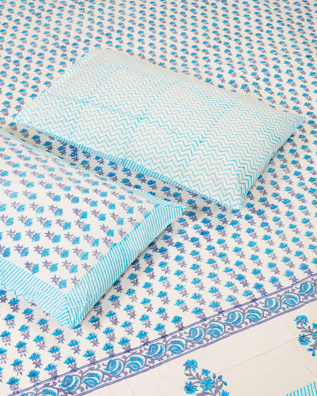 100x108 inch king size cotton bedsheet and matching chevron pillow covers styled with a traditional sky blue and periwinkle floral bud handblock print.