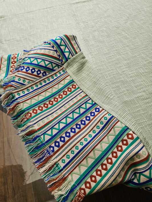Colorful patterned fabric with tassels on a textured surface