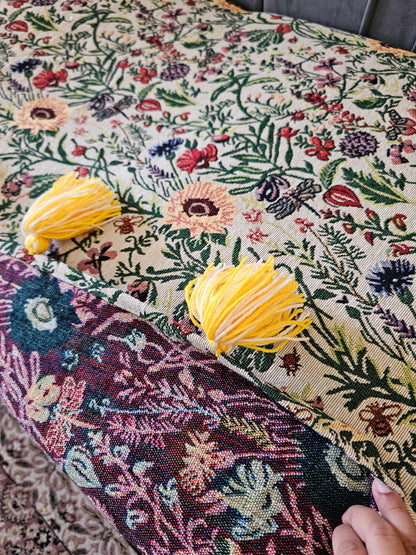 Close-up of a floral fabric with yellow tassels on a textured surface