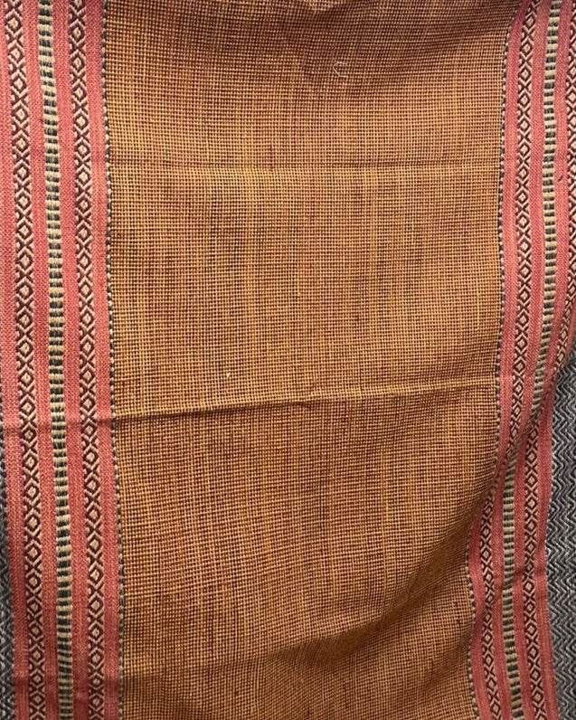 Terracotta rust cotton flatweave area rug with detailed charcoal grey and pink geometric border bands styled in a cozy warm living room.