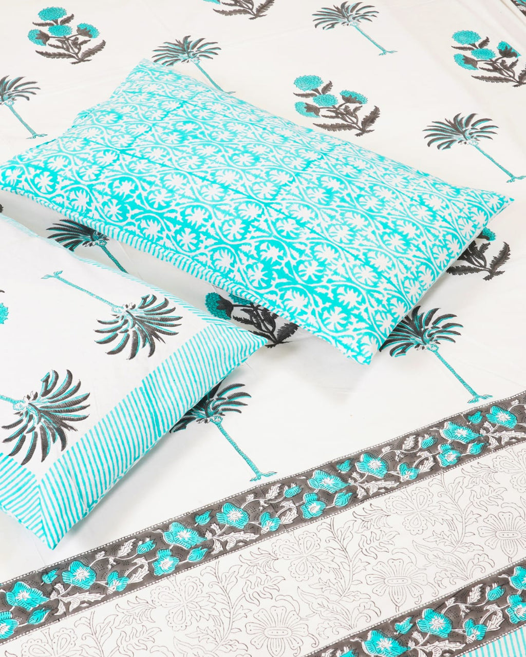 100x108 inch king size cotton bedsheet and matching striped pillow covers styled with a traditional turquoise floral and grey palm tree handblock print.