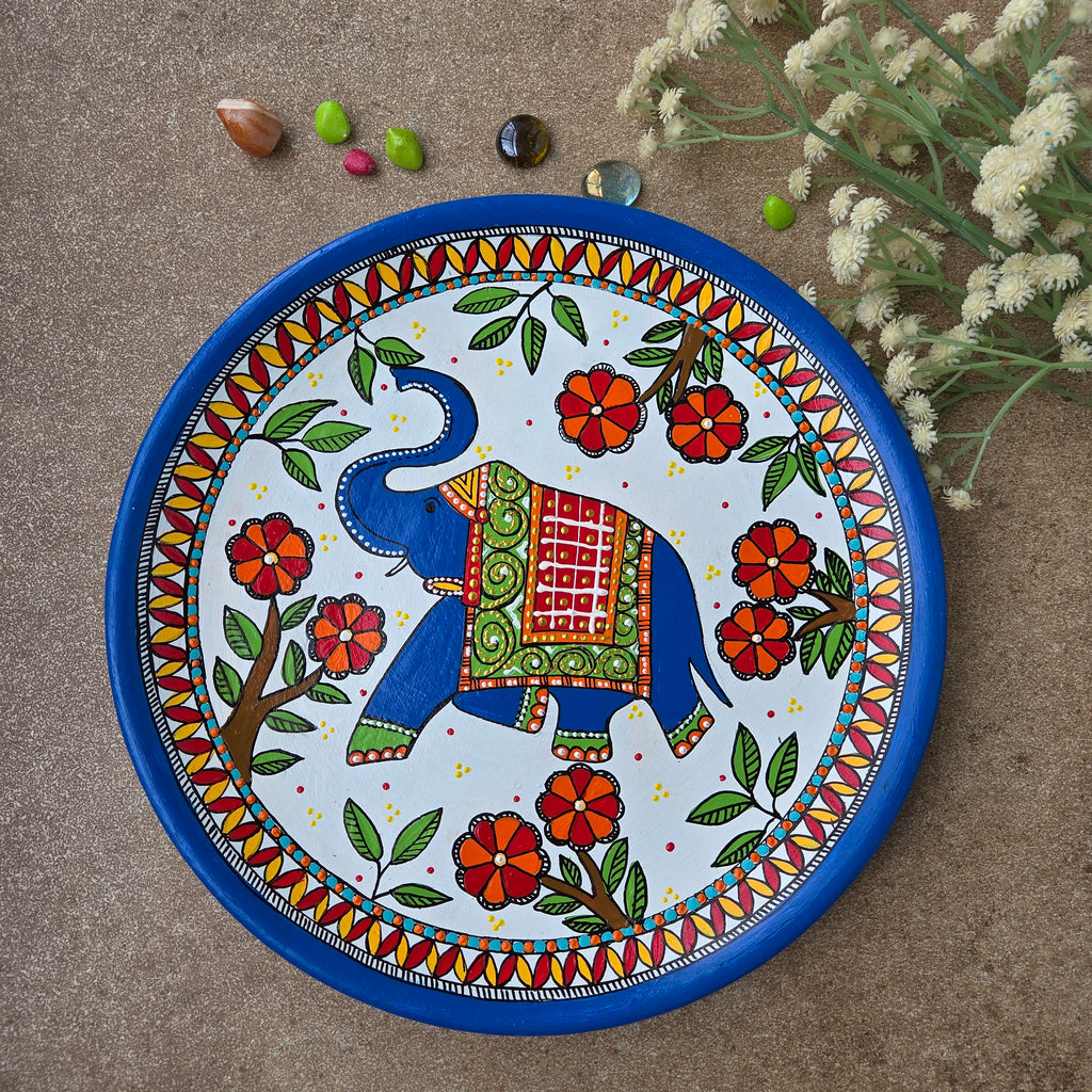 Intricate Madhubani royal elephant folk art hand-painted on an 8-inch terracotta wall plate finished with a deep blue rim.