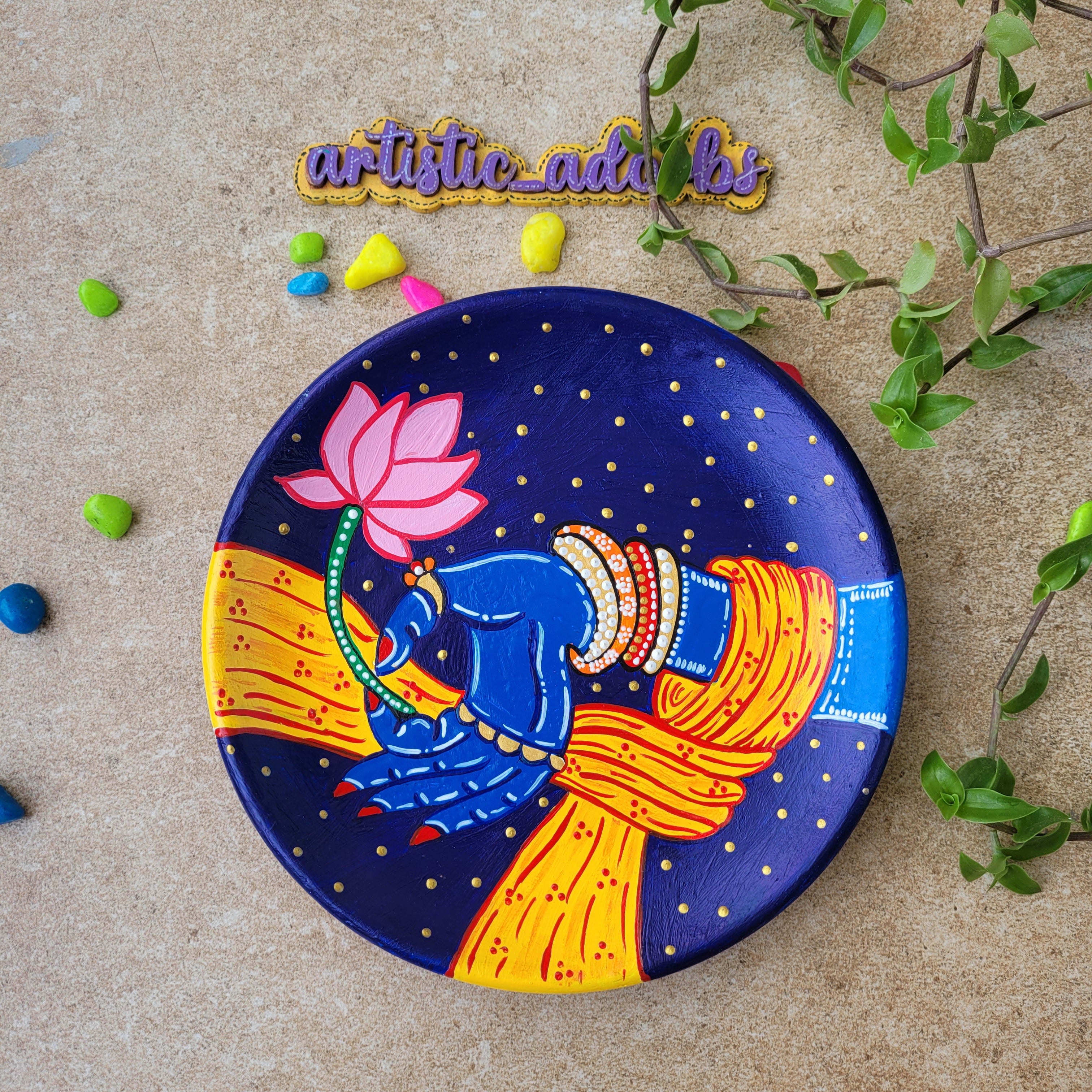 Dark blue Pichwai clay wall plate depicting Lord Shrinathji's blue hand holding a pink lotus blossom.