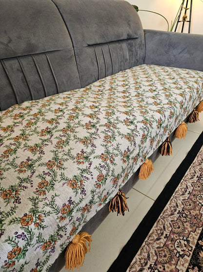 Floral-patterned throw blanket with tassels on a gray sofa