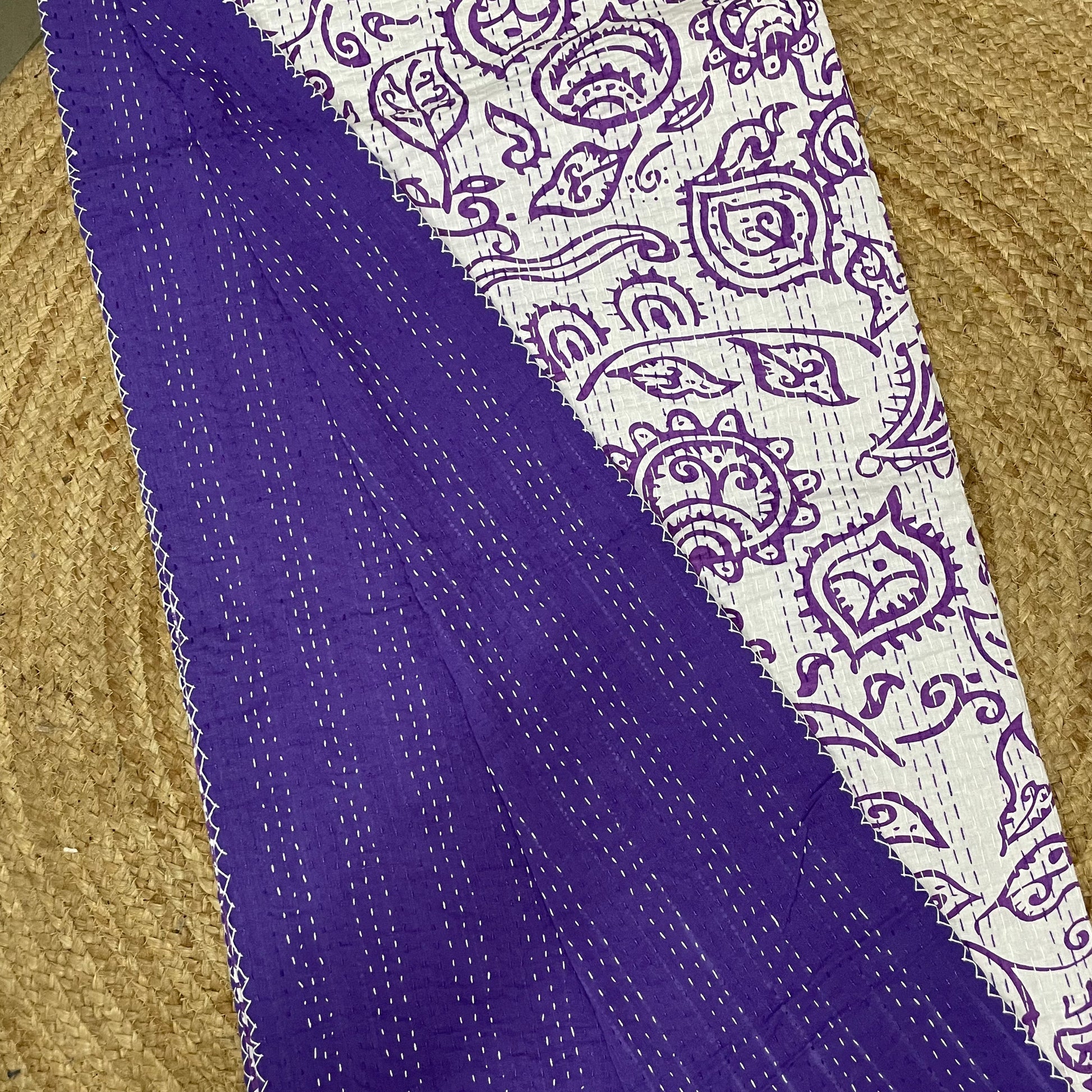 Purple fabric with white paisley pattern on a textured surface