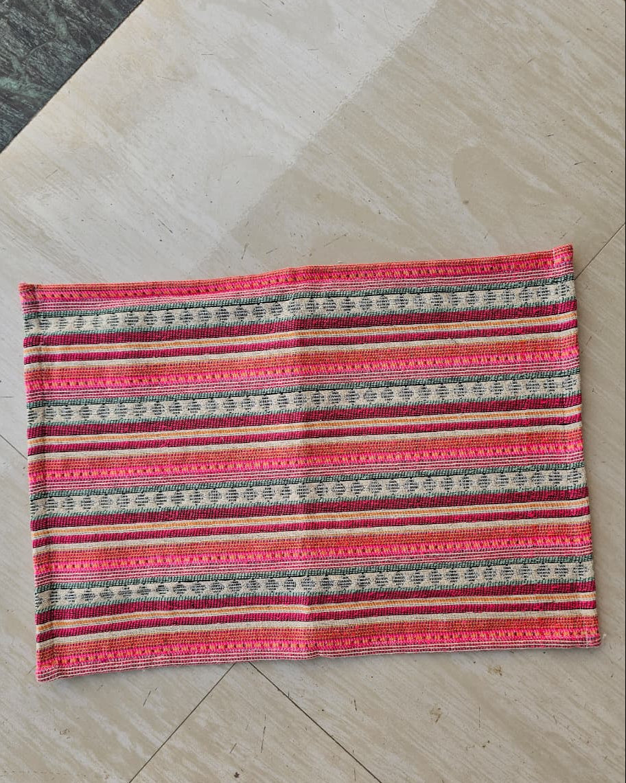 Rectangular handwoven cotton table placemat featuring horizontal hot pink, orange, green, and cream striped geometric patterns laid flat.