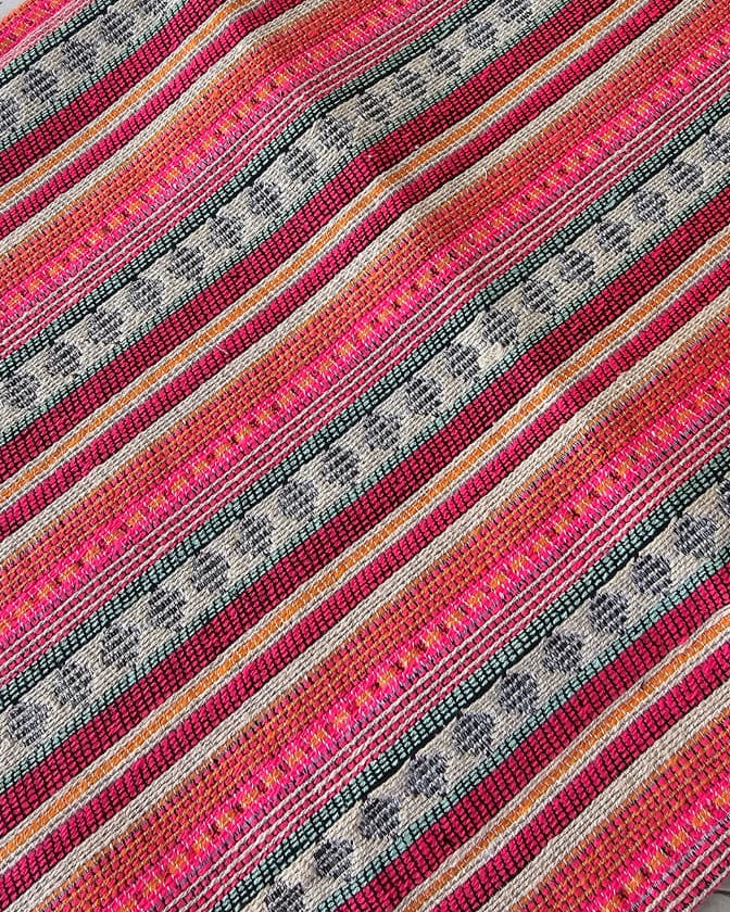 Rectangular handwoven cotton table placemat featuring horizontal hot pink, orange, green, and cream striped geometric patterns laid flat.