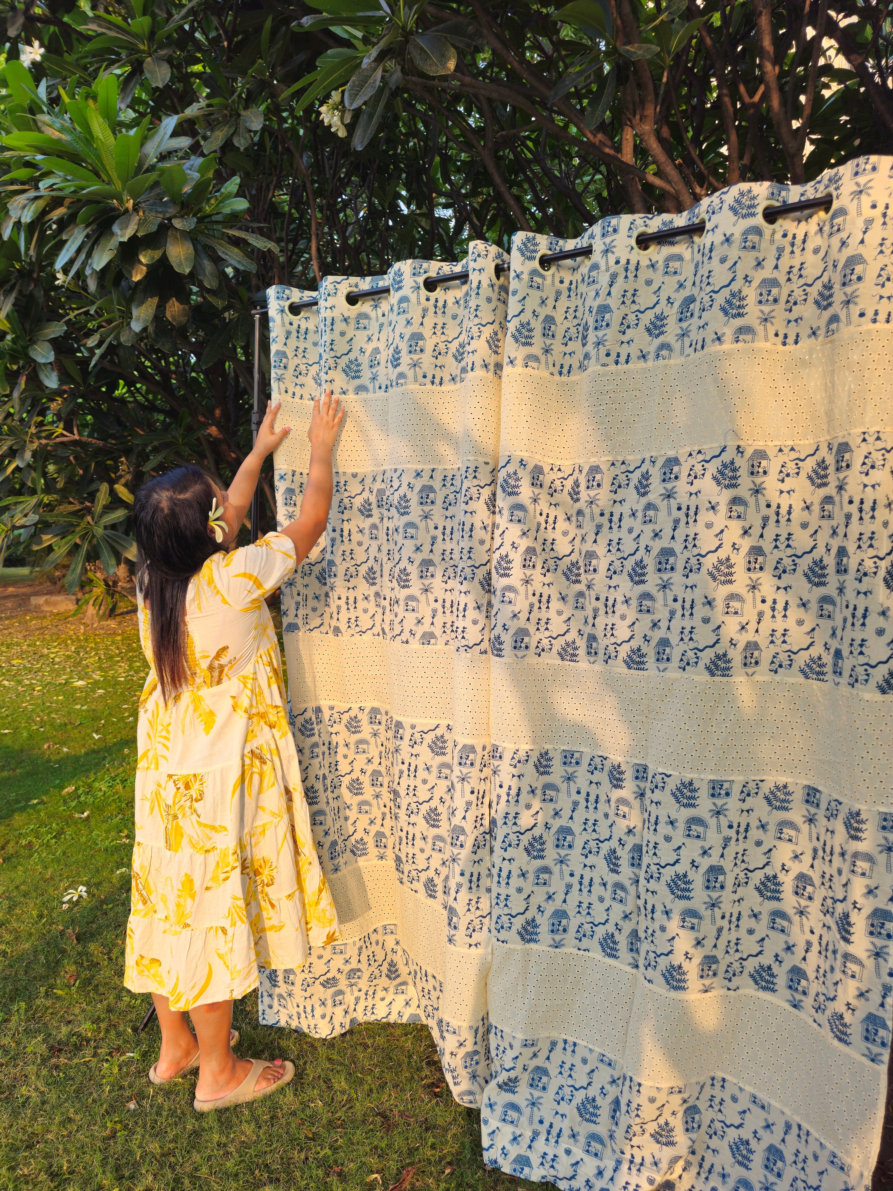 Woman hanging blue and white patterned curtains outdoors