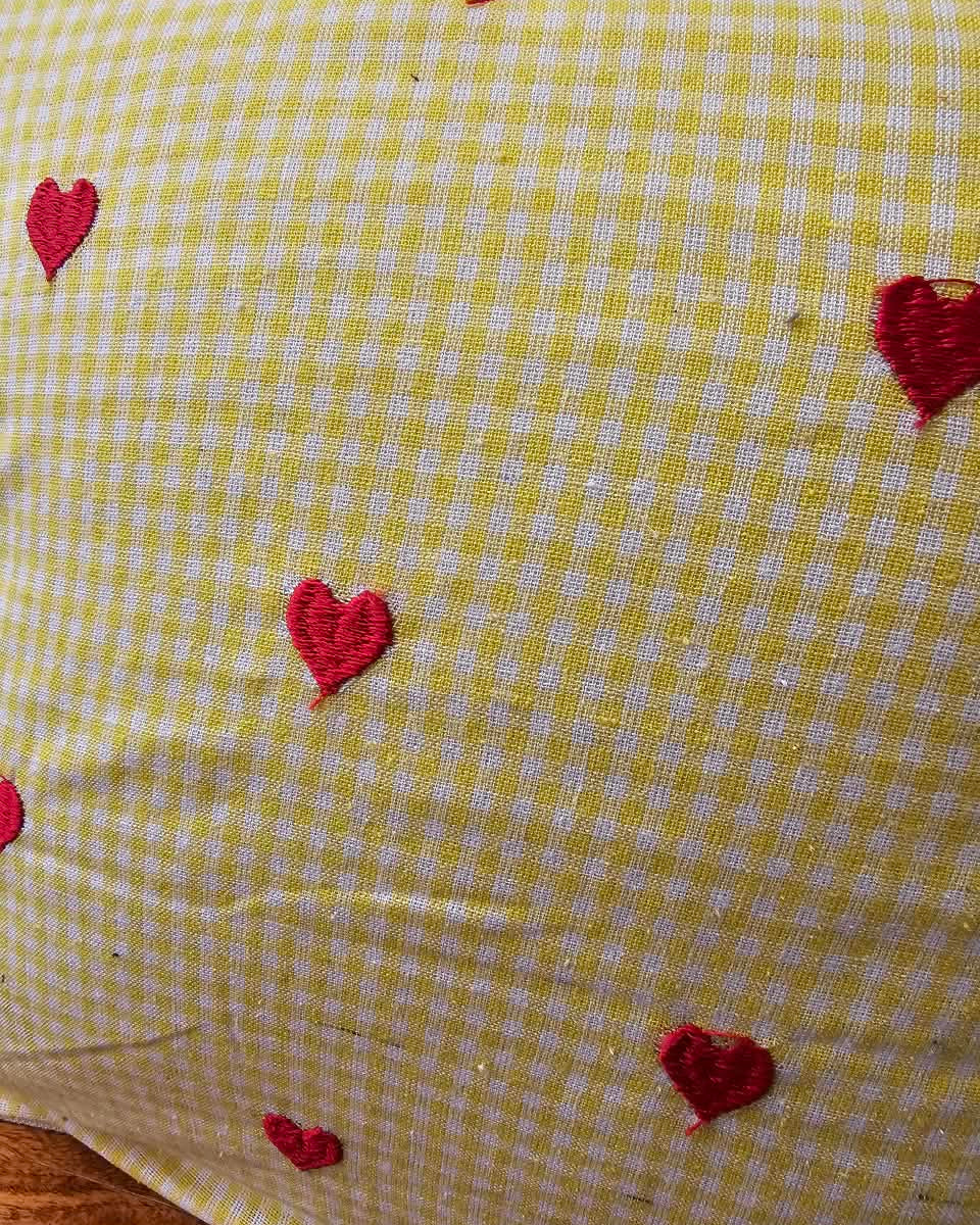 Yellow gingham check cotton cushion cover adorned with charming hand-embroidered red heart motifs.