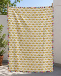Close-up of a handmade reversible Kantha cotton baby quilt showing the solid neutral reverse side with multi-colored hand stitching folded over the yellow turtle print and colorful triangle edge binding.