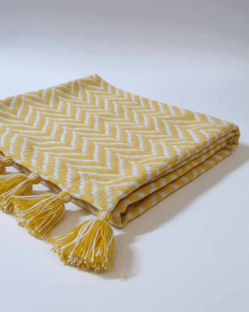 Yellow and white chevron Jacquard cotton dining table runner featuring a bold zigzag pattern and two-tone woolen hanging tassels, with Vasaca brand labels.