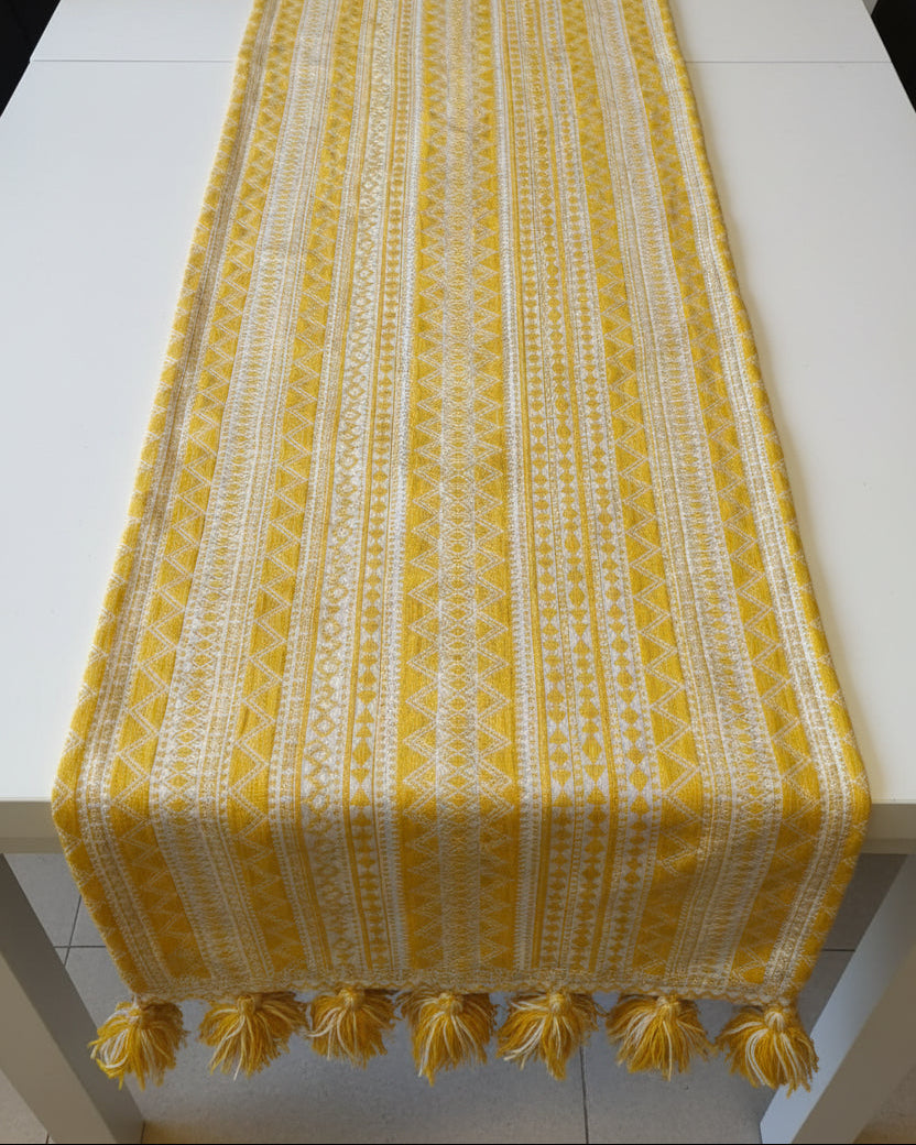 Yellow and white geometric Jacquard cotton dining table runner featuring intricate Aztec patterns and two-tone woolen hanging tassels, with Vasaca brand labels.