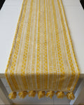 Yellow and white geometric Jacquard cotton dining table runner featuring intricate Aztec patterns and two-tone woolen hanging tassels, with Vasaca brand labels.