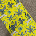 Fabric with a jungle-themed pattern featuring animals and plants on a yellow background.