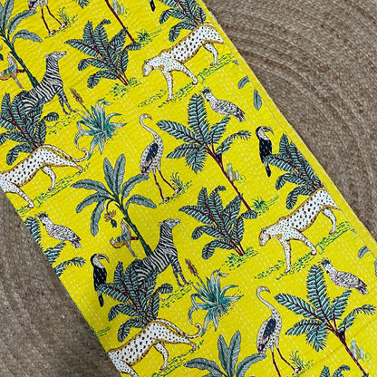 Fabric with a jungle-themed pattern featuring animals and plants on a yellow background.