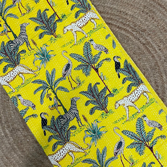 Fabric with a jungle-themed pattern featuring animals and plants on a yellow background.